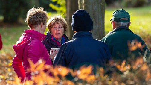 A group of four people talking outside in autumn